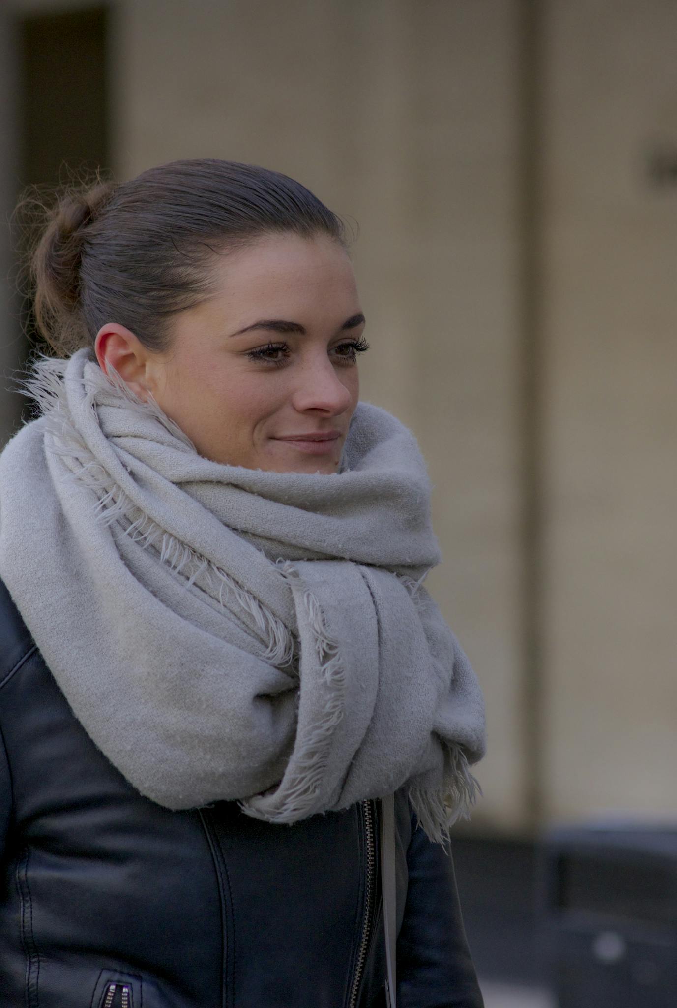 Smiling woman wearing a winter scarf outdoors on a cool day in New York City.